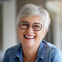 Older woman with black glasses smiling