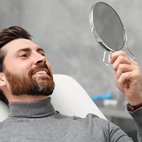 Man looking at repaired smile in dentist’s office
