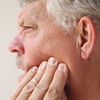 Man experiencing some soreness after dental implant surgery