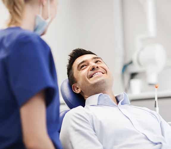 Male patient listens to dentist explain dental implant salvage