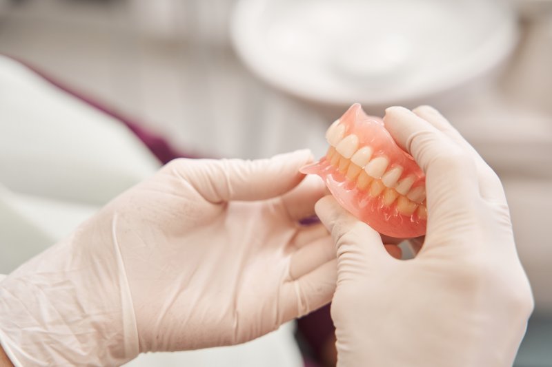 person holding set of full dentures