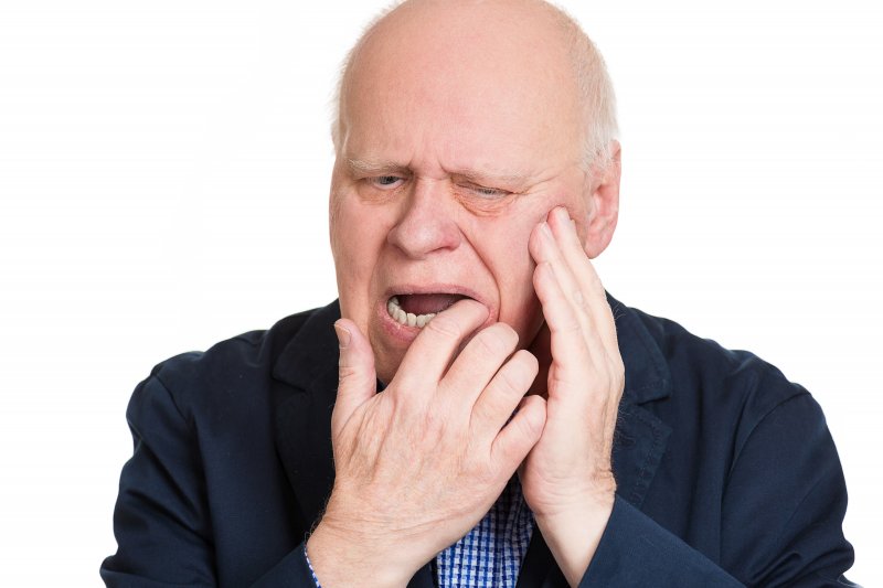 man experiencing soreness while wearing dentures