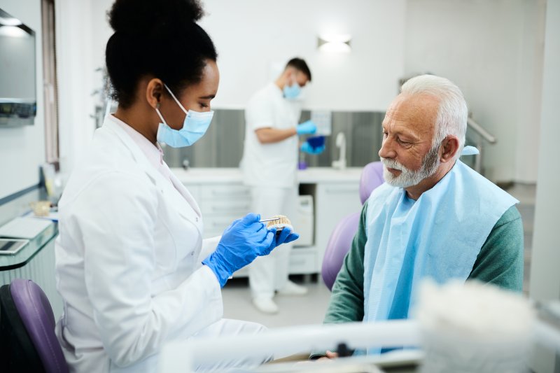 dentist discussing how a denture is relined with older male patient